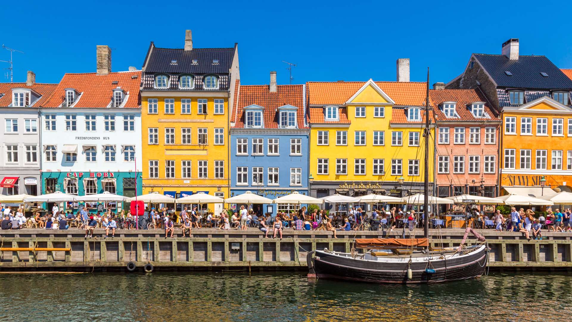 Nyhavn in Copenhagen - Colourful buildings and people enjoying the sun