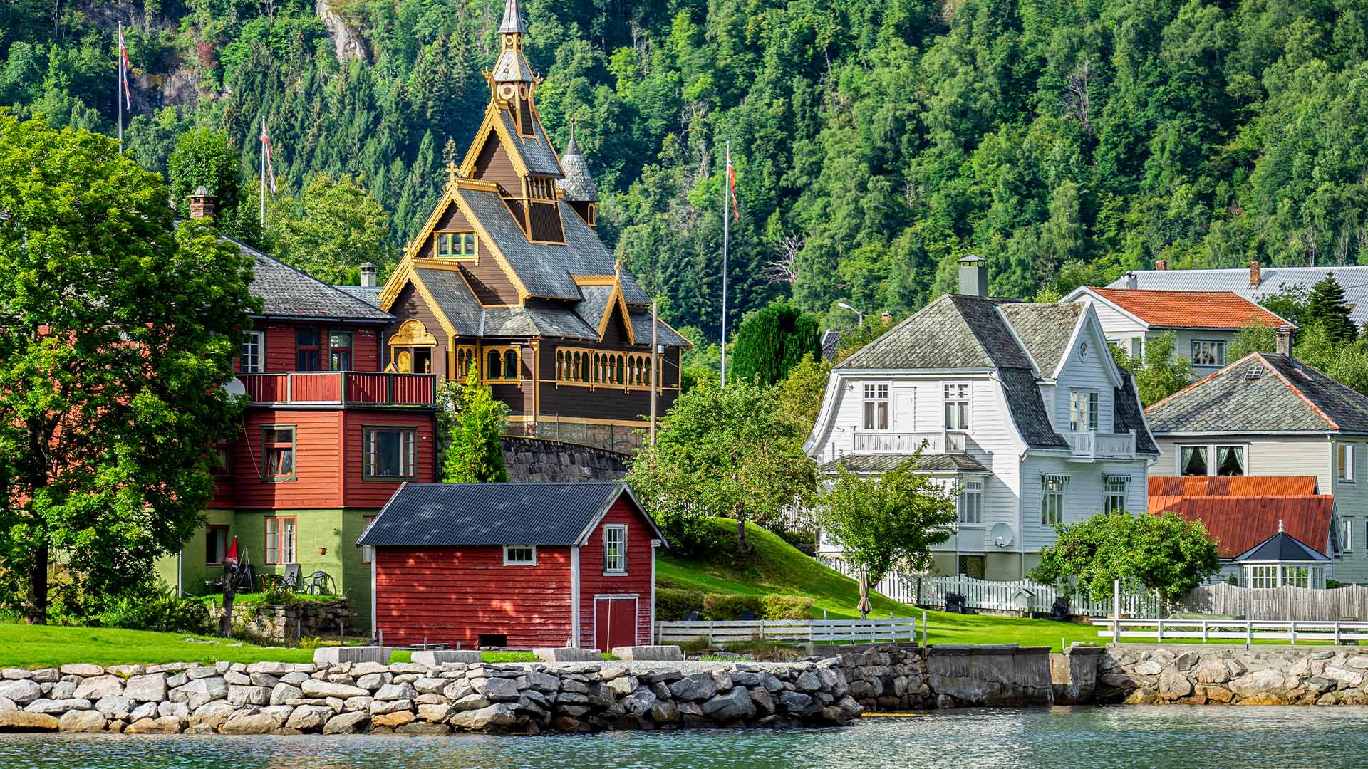 Traditional wooden houses and Historic St. Olaf’s Church along Sognefjord shore in Balestrand