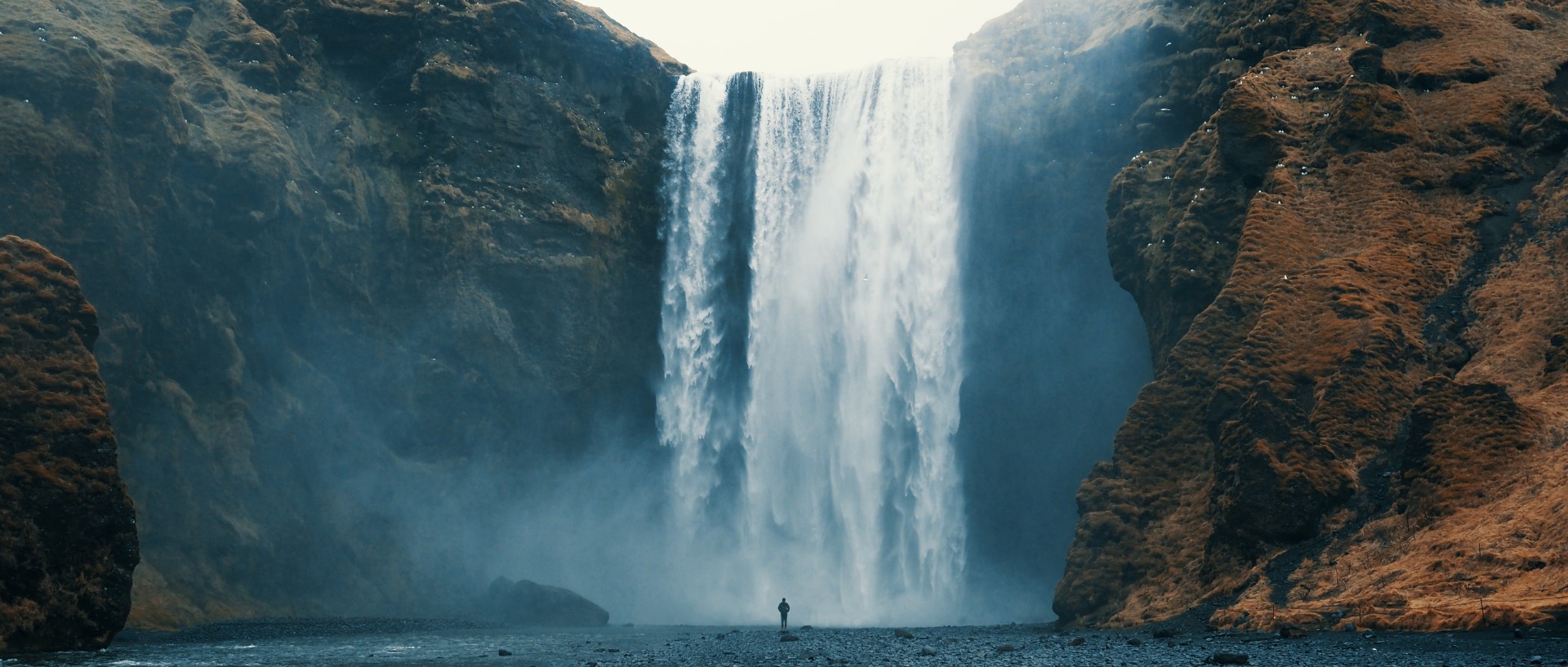 Person admiring Skógafoss waterfall in Iceland