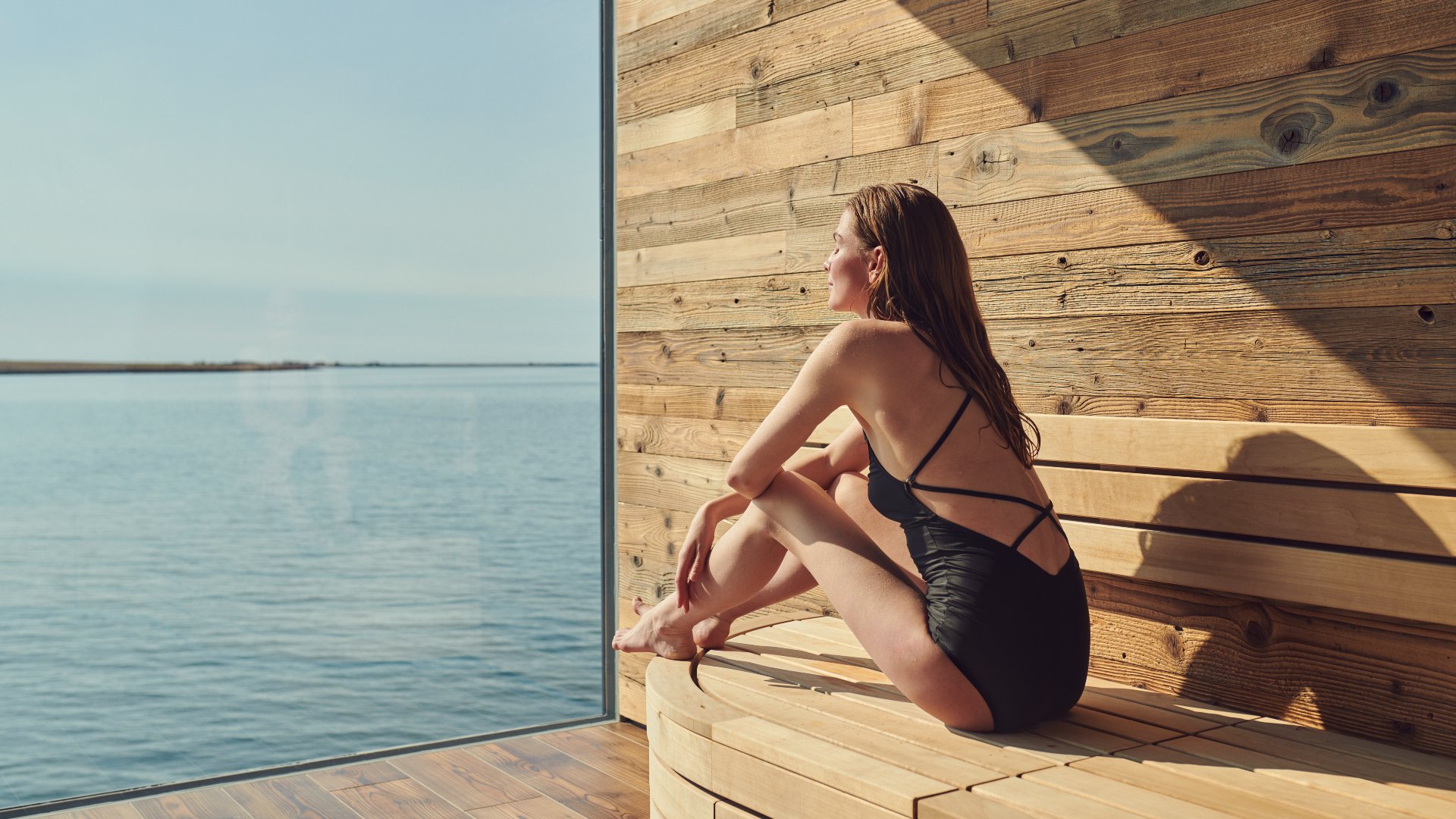 woman sitting in the sauna with a sea view at sky lagoon