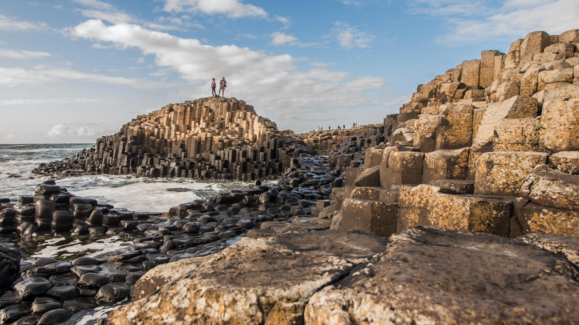 People standing on top of rock columns at the Giant's Causeway
