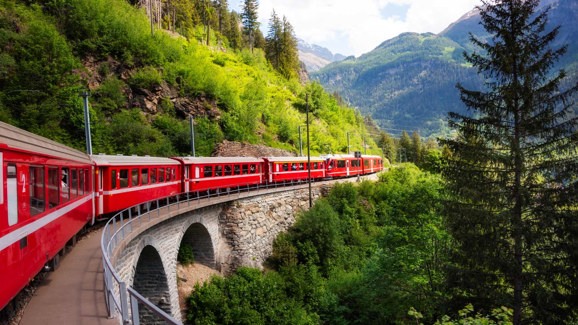 Red Swiss train traveling through alpine mountains