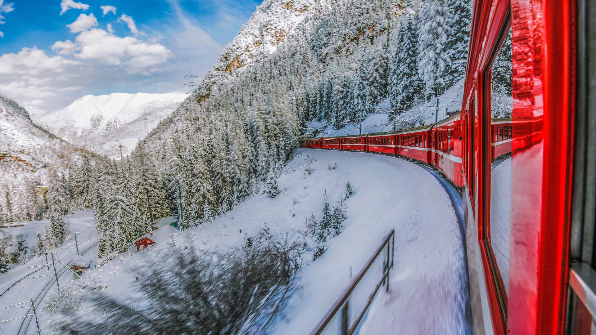 Red train crossing snow-covered Swiss Alps