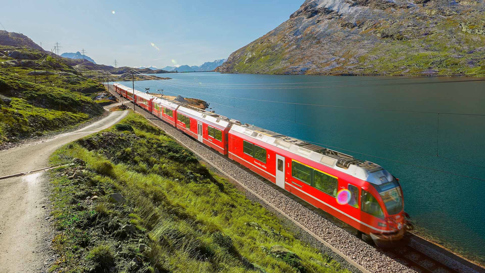 Scenery of a train of Rhaetian Railway dashing along Lago Bianco in Bernina Pass