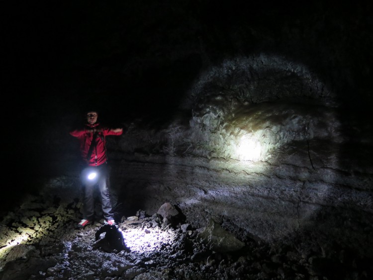 The small group stops to see the walls marked with signs of where the lava flowed through this tube roughly 8000 years ago. Ægir likens the horizontal markings to what one would find on a dry creek bed.