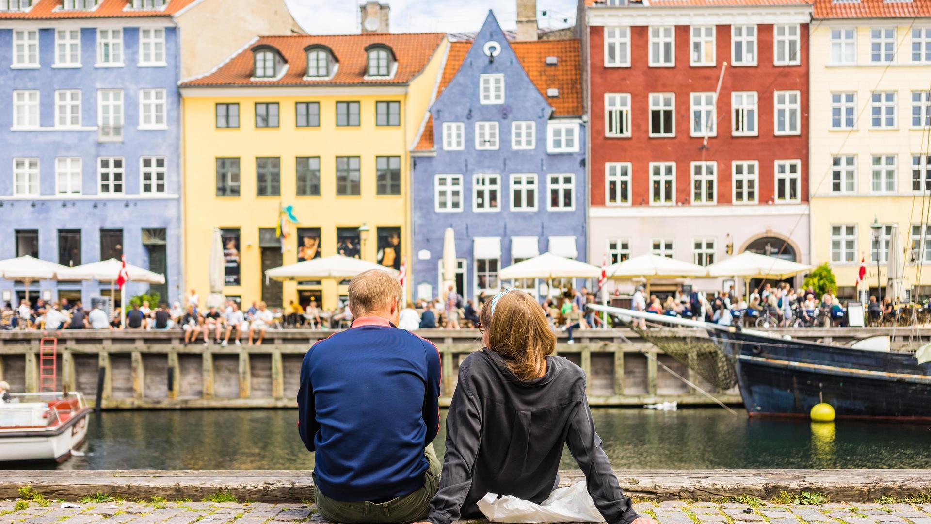 A couple enjoying a view of the river and colourful houses in Copenhagen