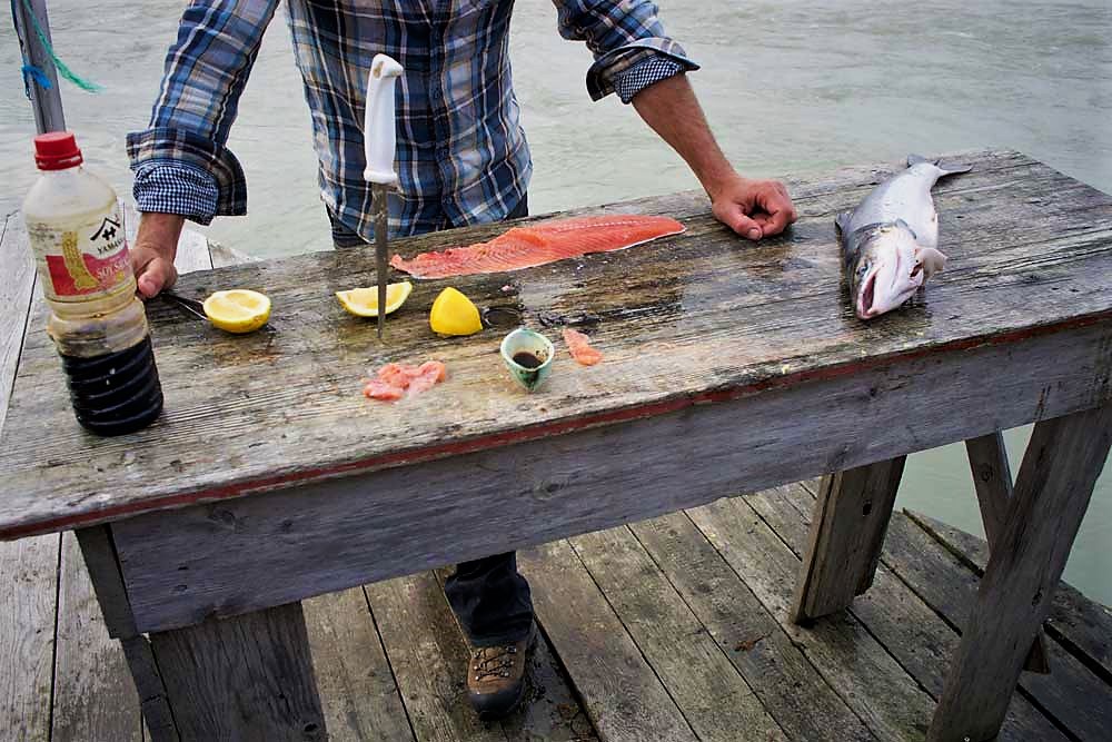 Hákon serves fresh salmon sashimi on the riverside.
