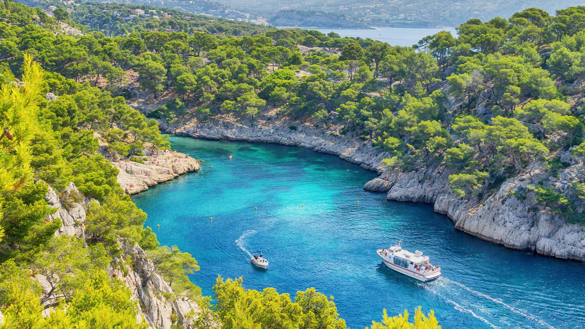 Aerial shot of Bay of Calanques’ turquoise waters with a few boats floating along