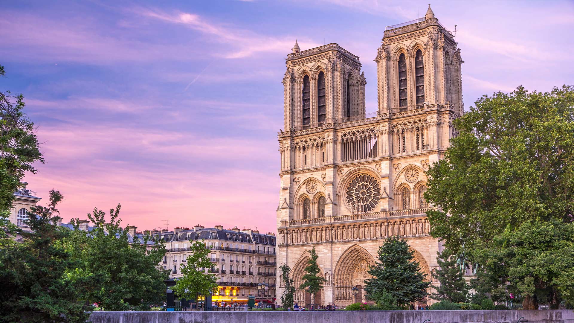 Front view of Notre Dame Cathedral at sunset with pink and purple skies