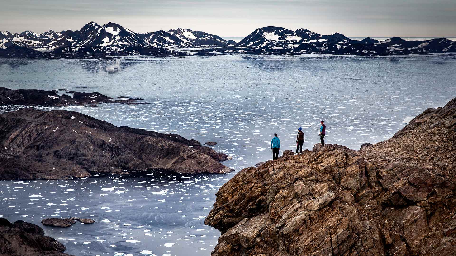 people standing at viewpoint by the icy sea