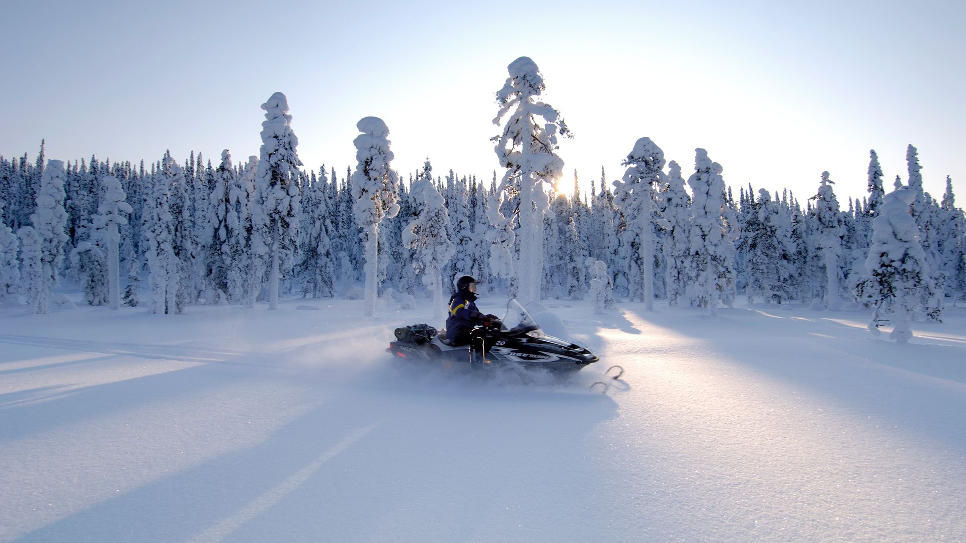 Snowmobile gliding through a pristine white forest in Finnish Lapland ©VisitFinland
