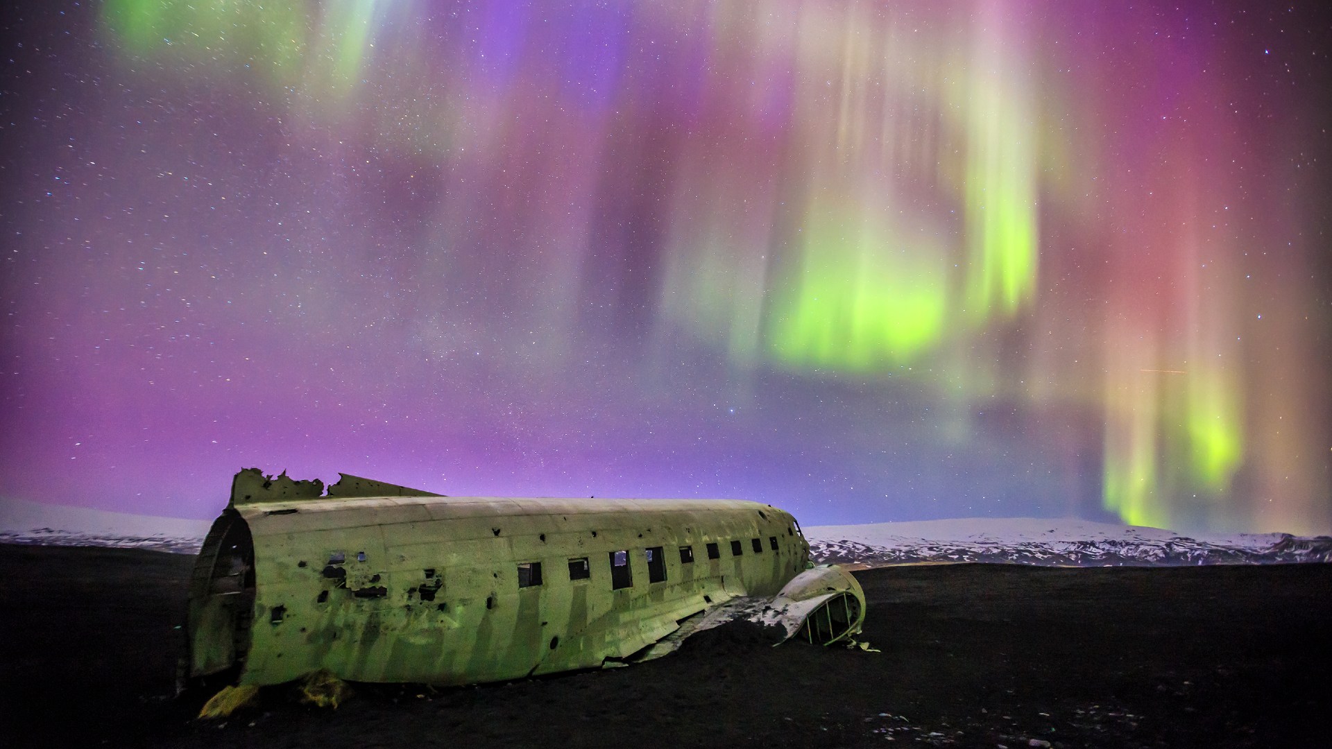 colourful northern lights and sky above beach and plane