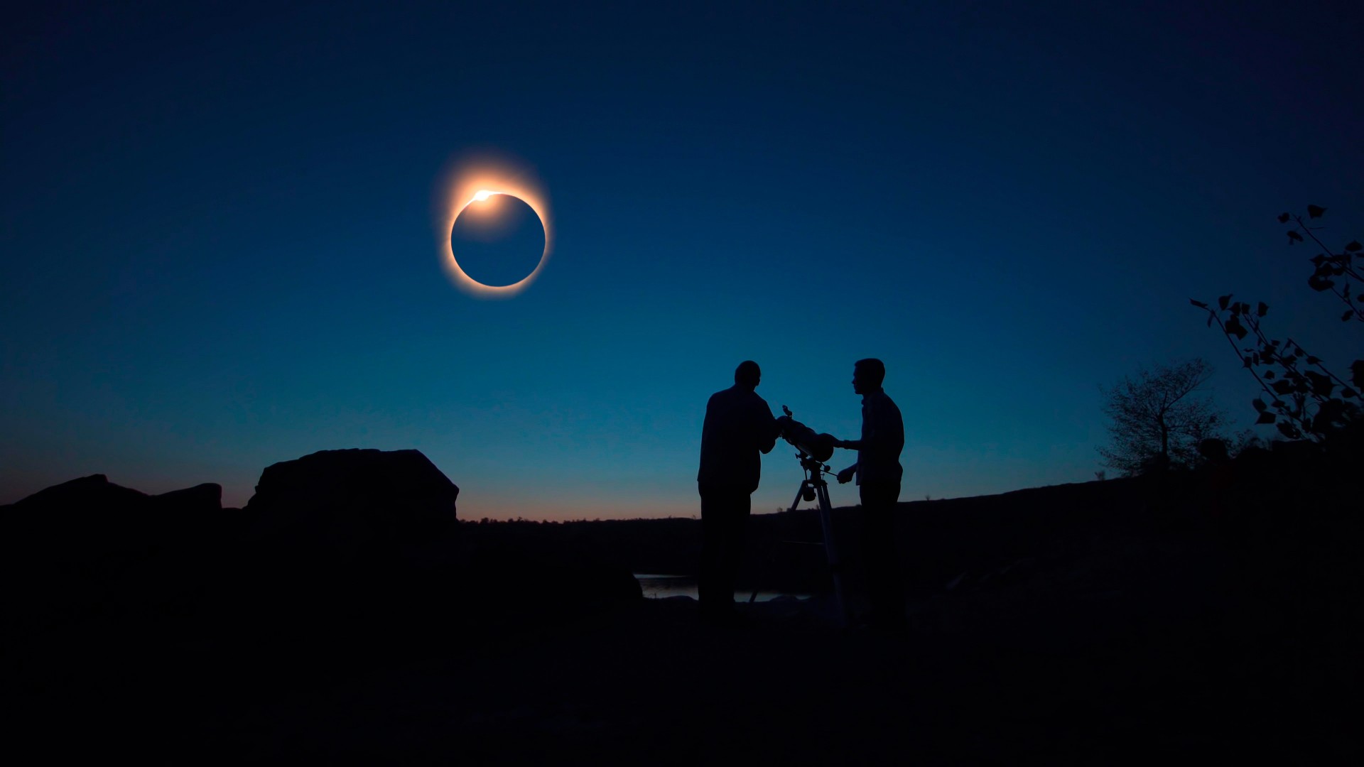 People with a telescope during a solar eclipse