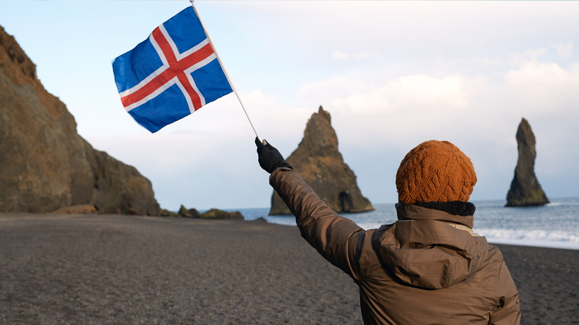Waving the Icelandic flag in Reynisfjara, Iceland
