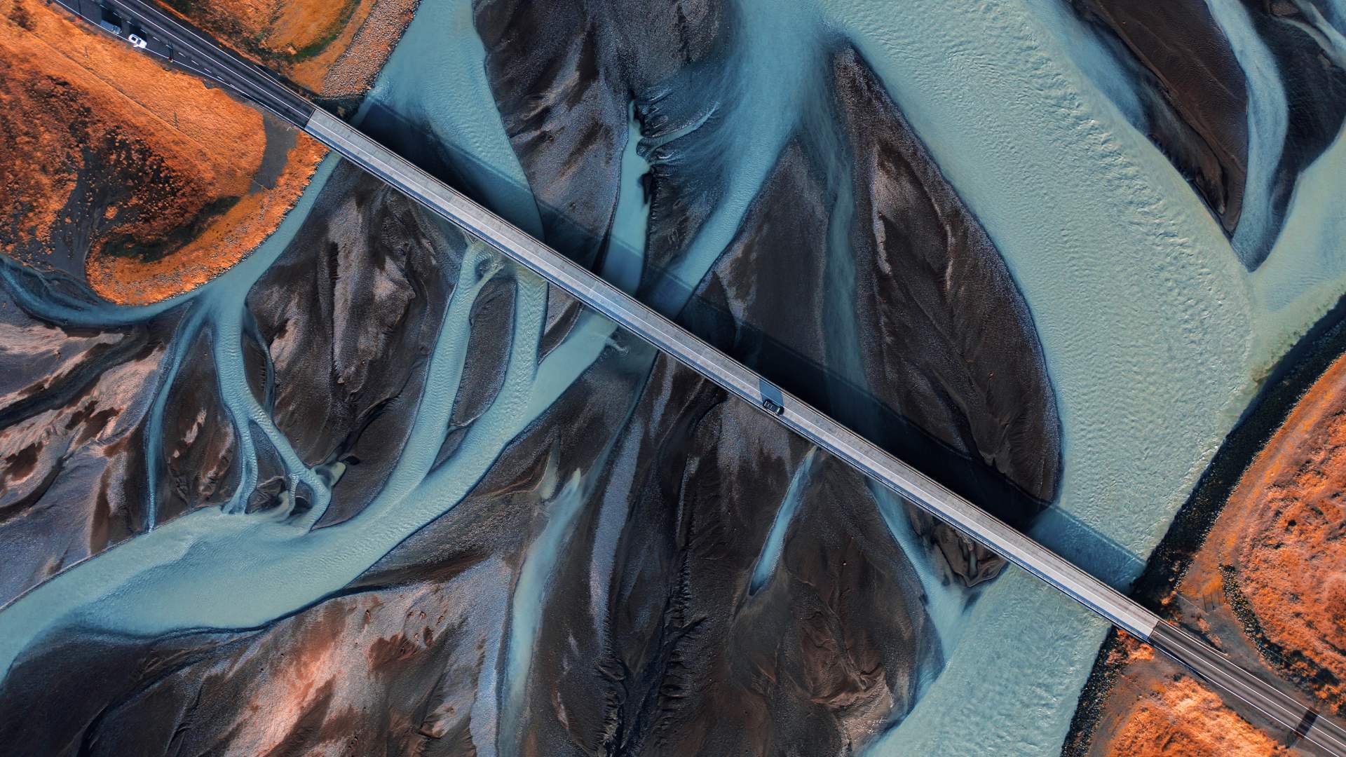 Car driving over a road bridge across a braided river in Iceland