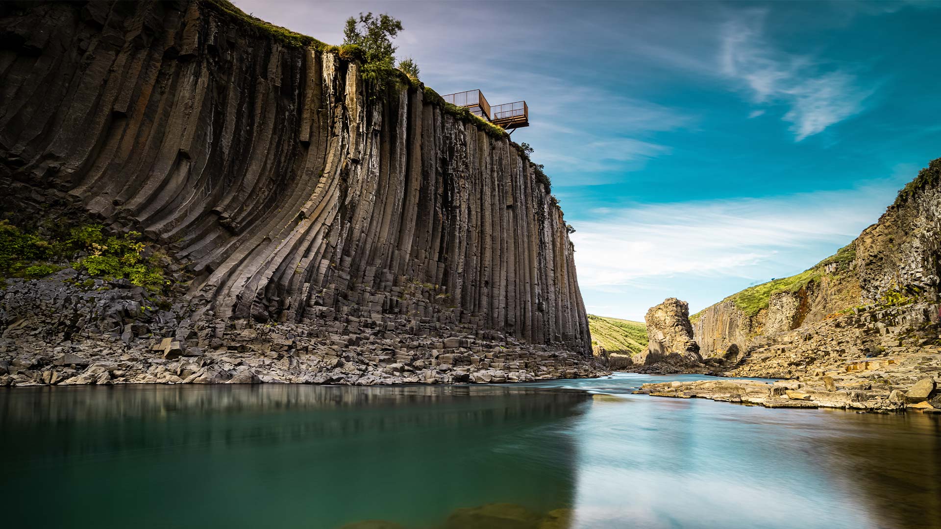 Towering basalt columns overlooking still blue waters.