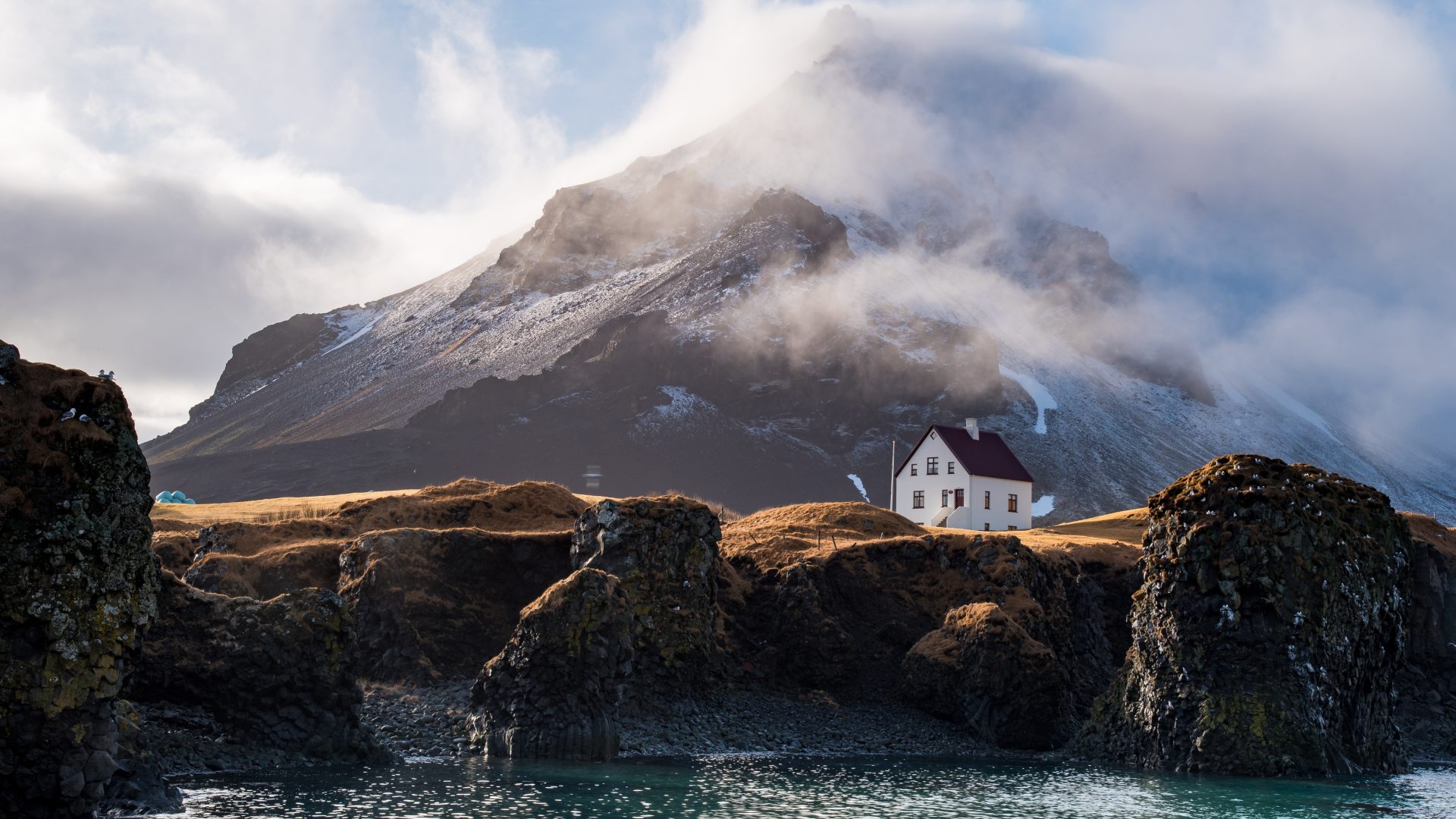 A white cottage sitting atop a rugged cliff.
