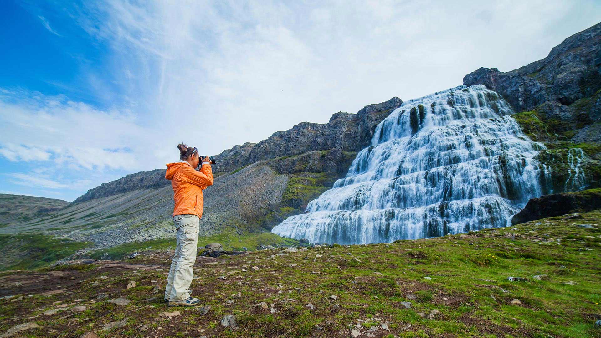 woman takin photo at dynjandi waterfall