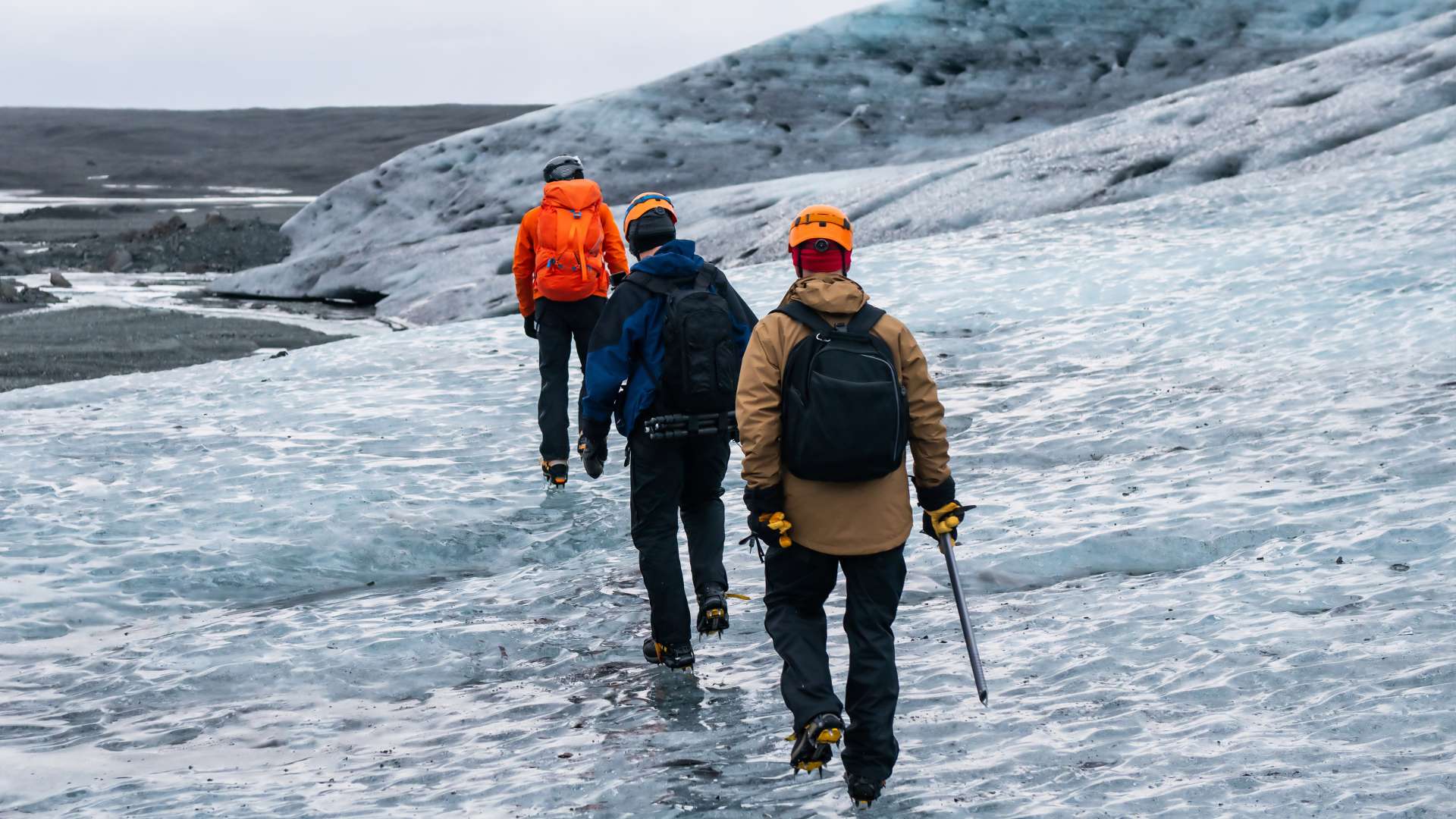 Tourists wearing helmets and crampons exploring the glacier surface.
