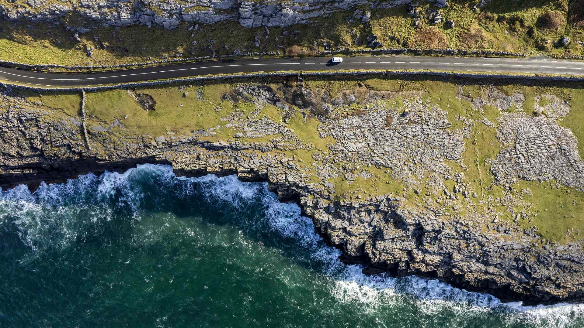 Aerial view of a car driving along a coastal road in the Burren, County Clare, Ireland