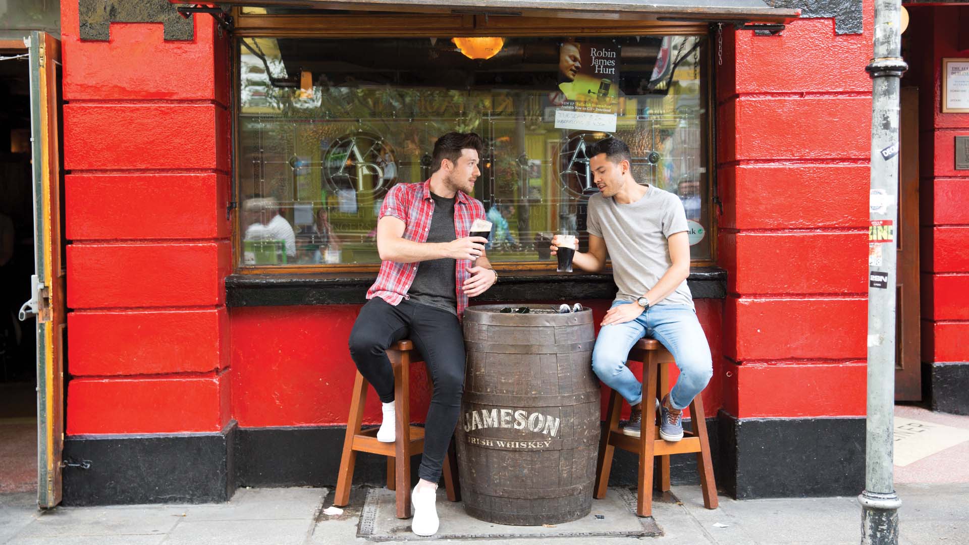 Two men drinking pints outside in Dublin's Temple Bar District, Ireland