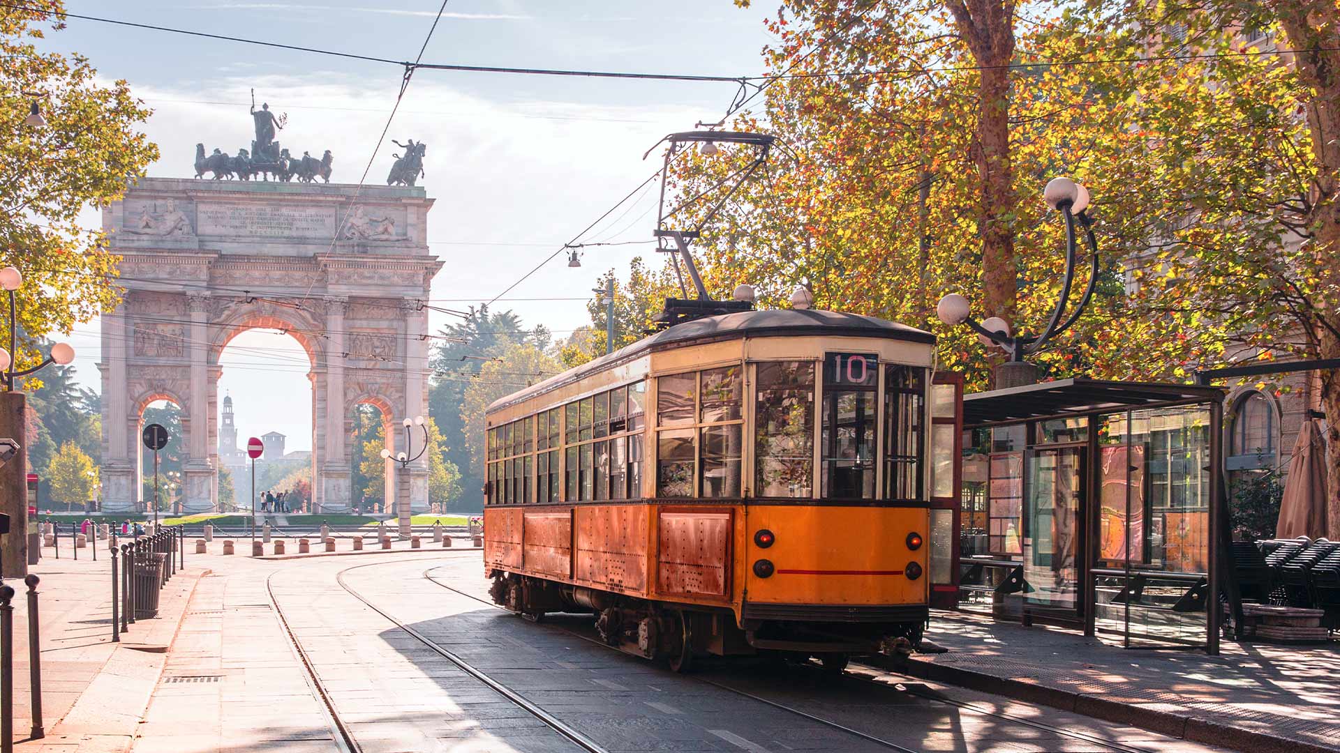 A vintage red red driving along a historic street in MIlan
