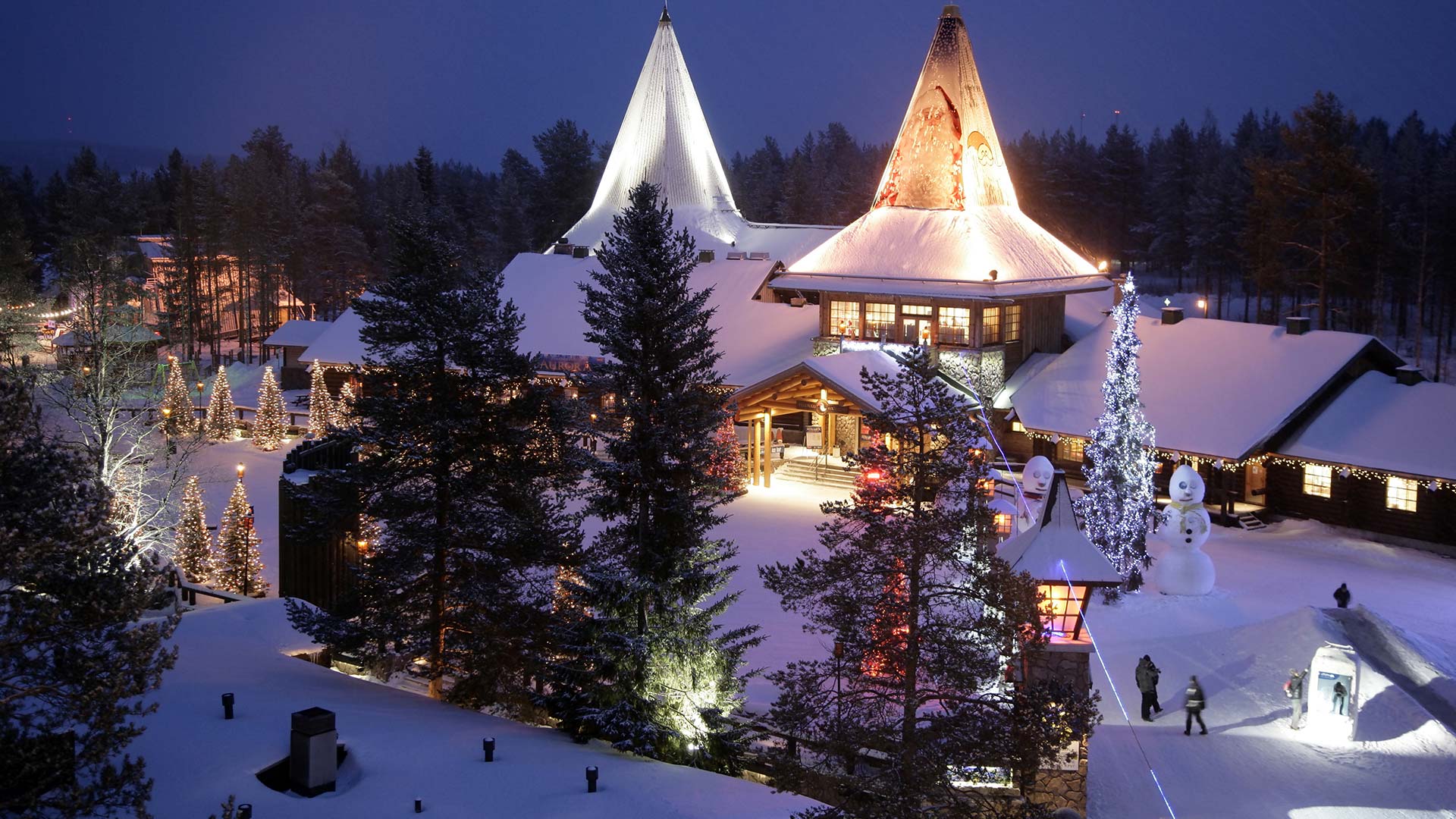 wooden buildings of santa claus village under snow