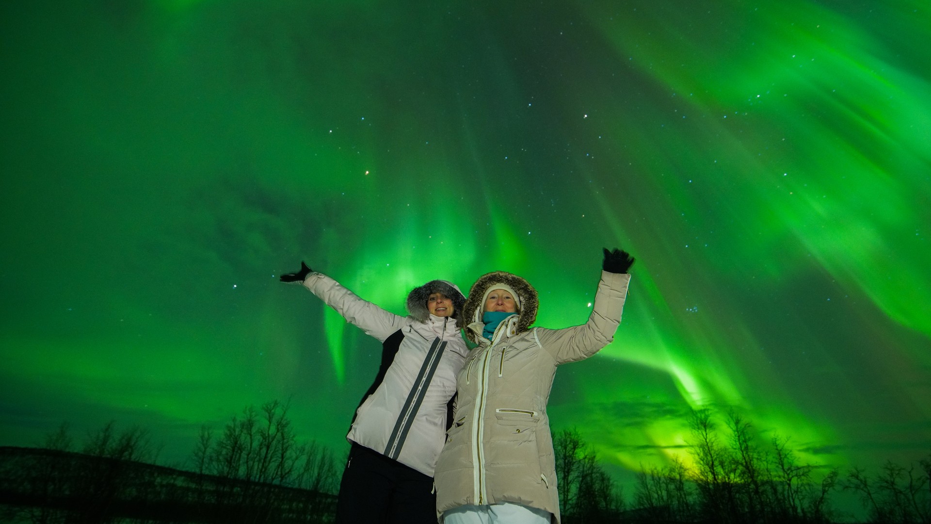 Two women enjoyed the green shimmering northern lights above them