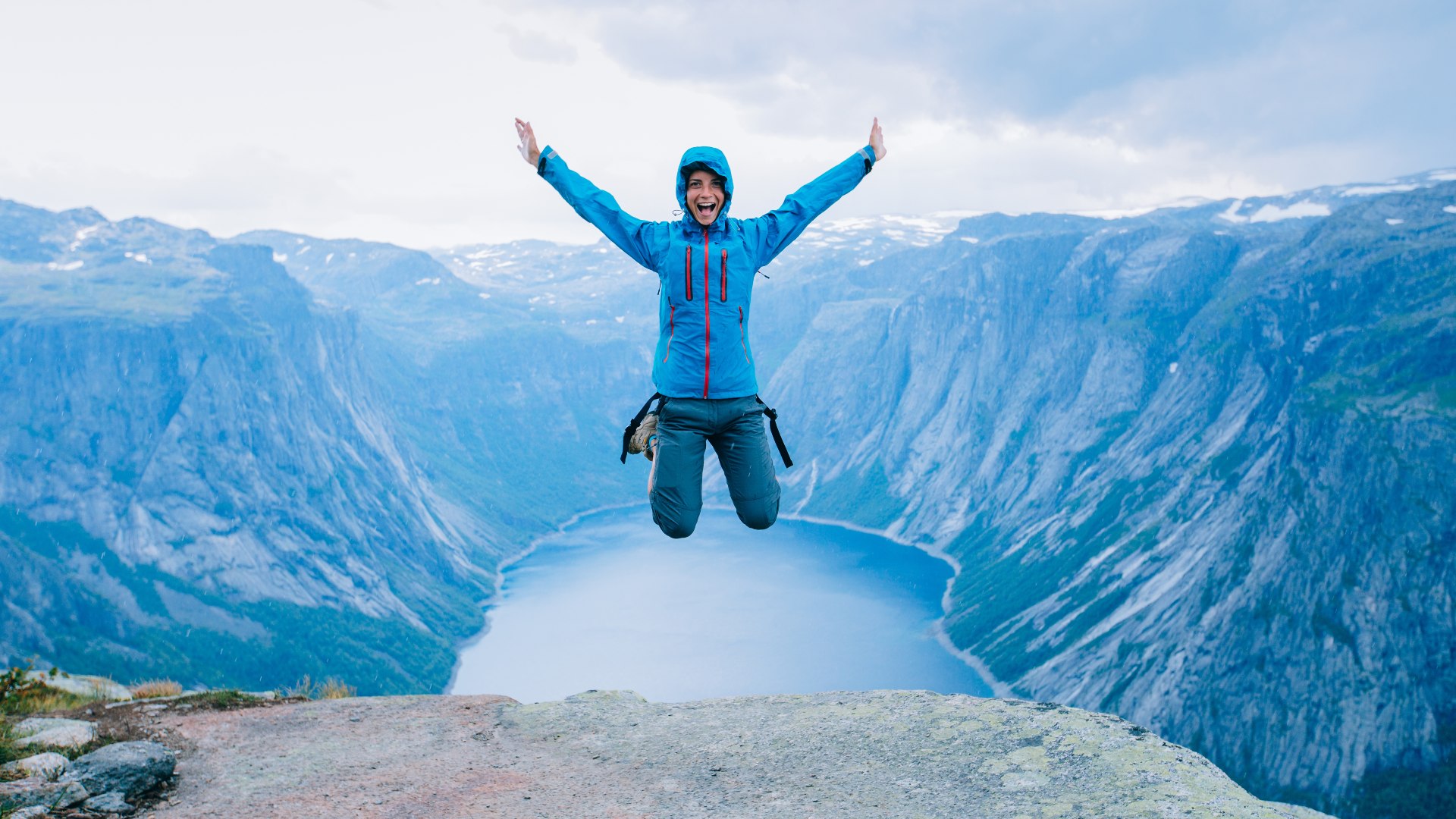 Hiker jumping in front of a Norwegian fjord view