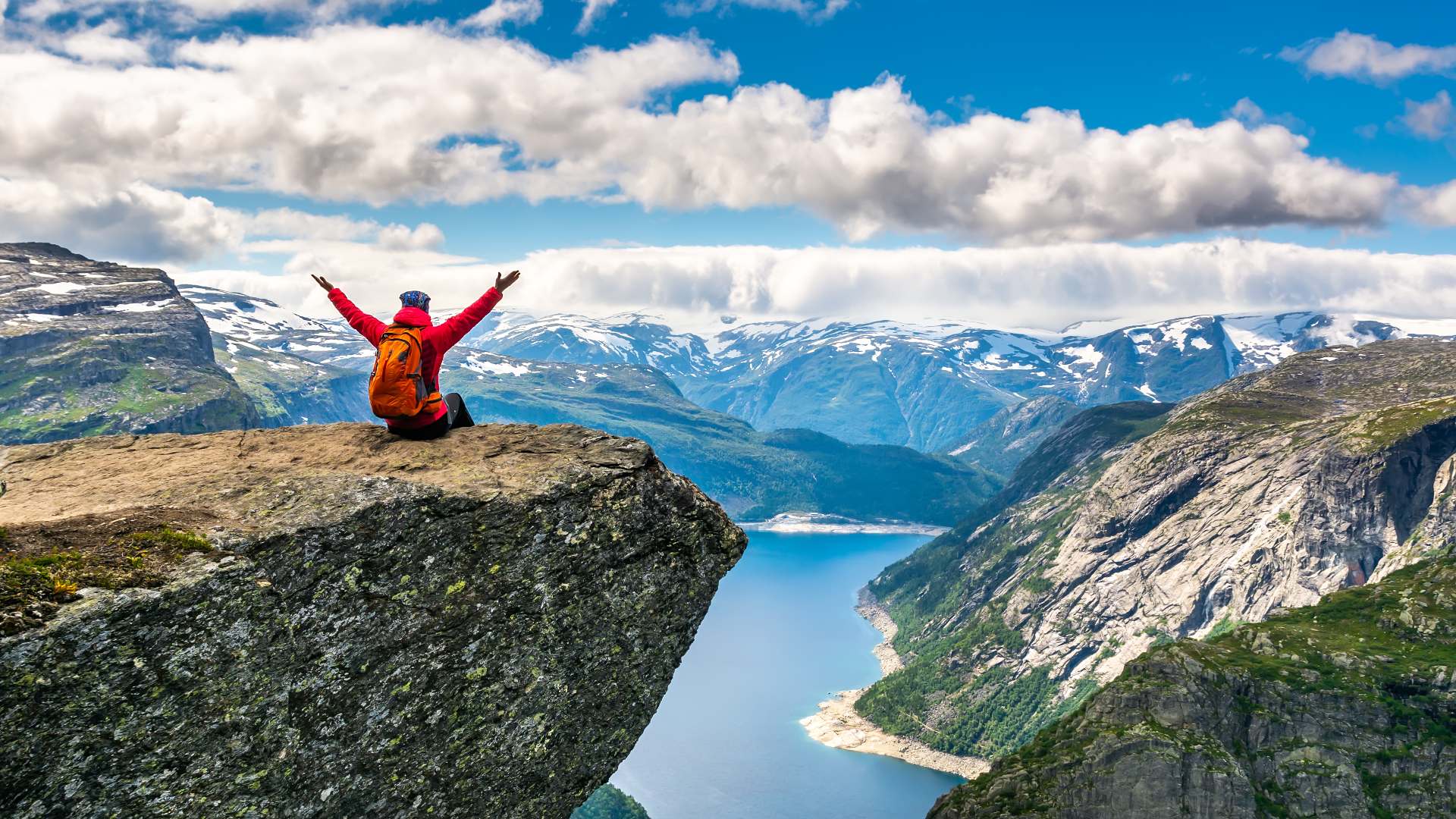 person sitting atop trolltunga cliff