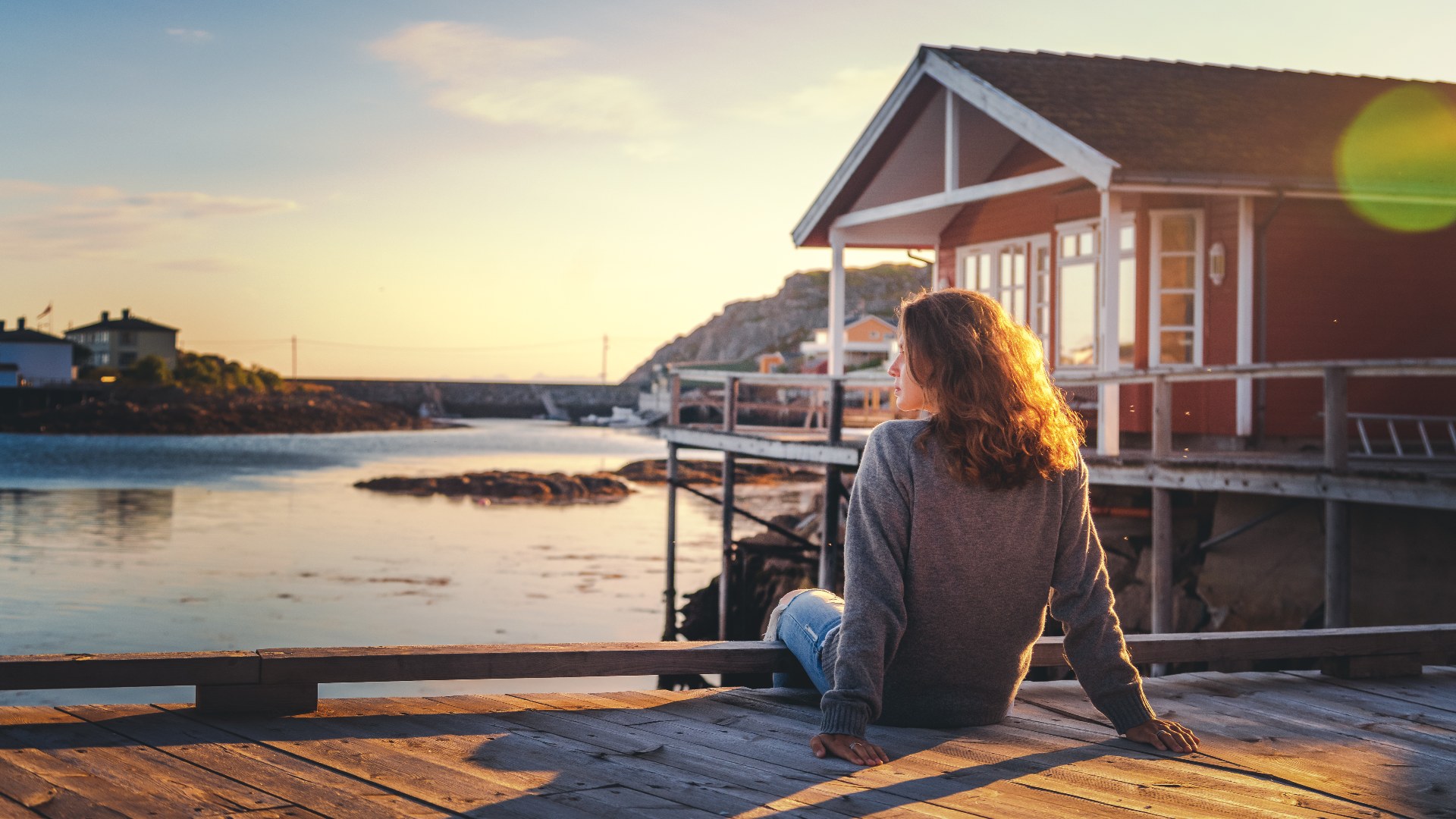 Person sitting next to a traditional Norwegian cabin