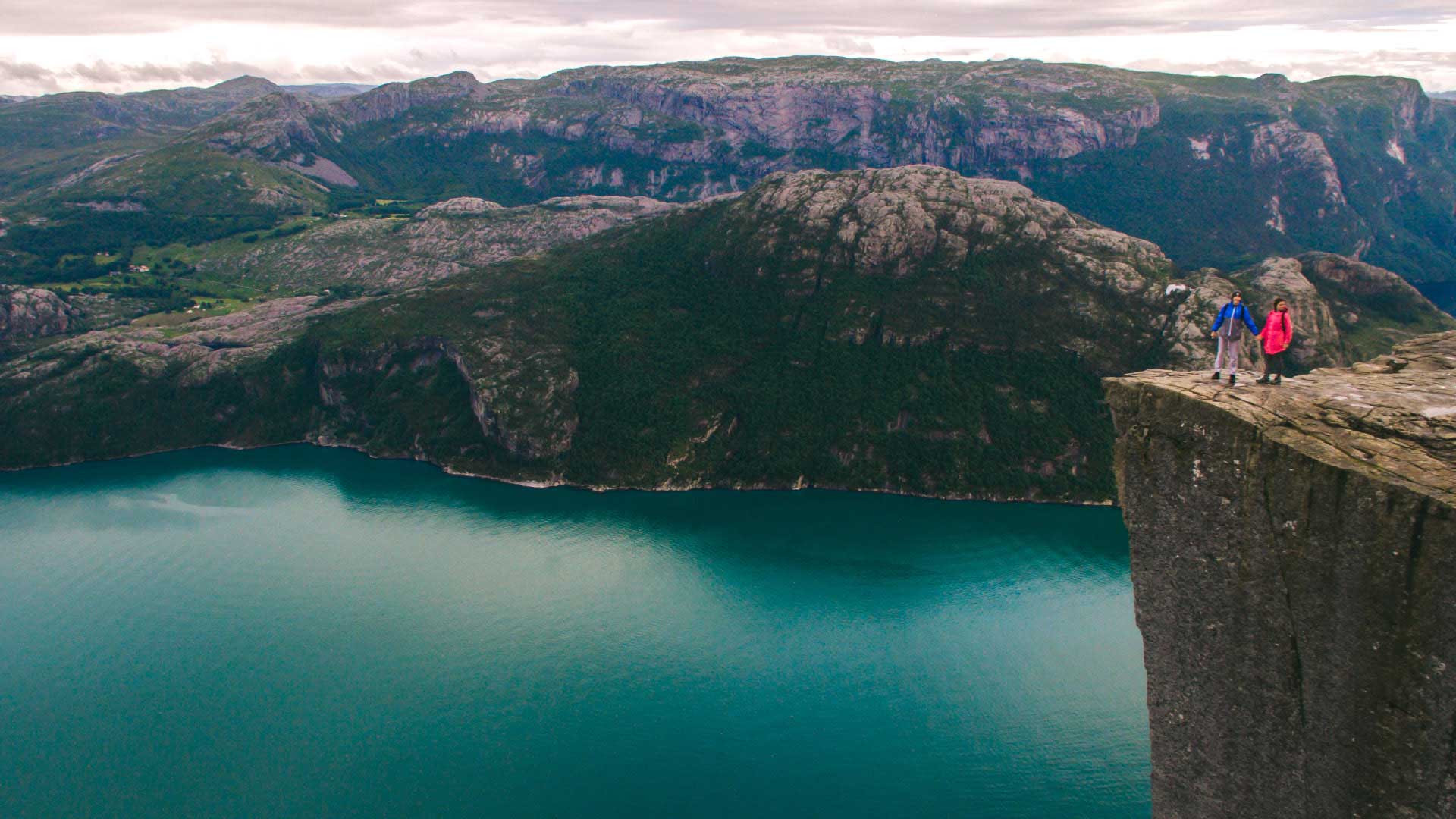 people standing on Pulpit Rock with view of the fjord below