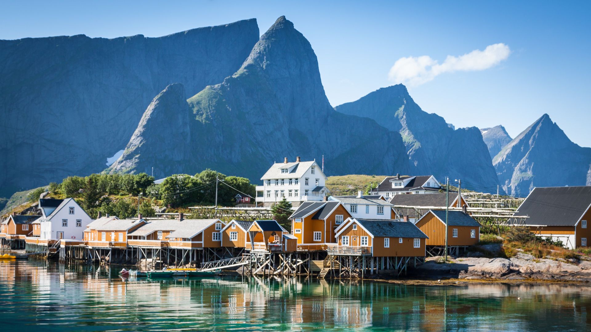 Houses perched at the waters edge, with towering mountains in the backdrop in the Lofoten Islands,