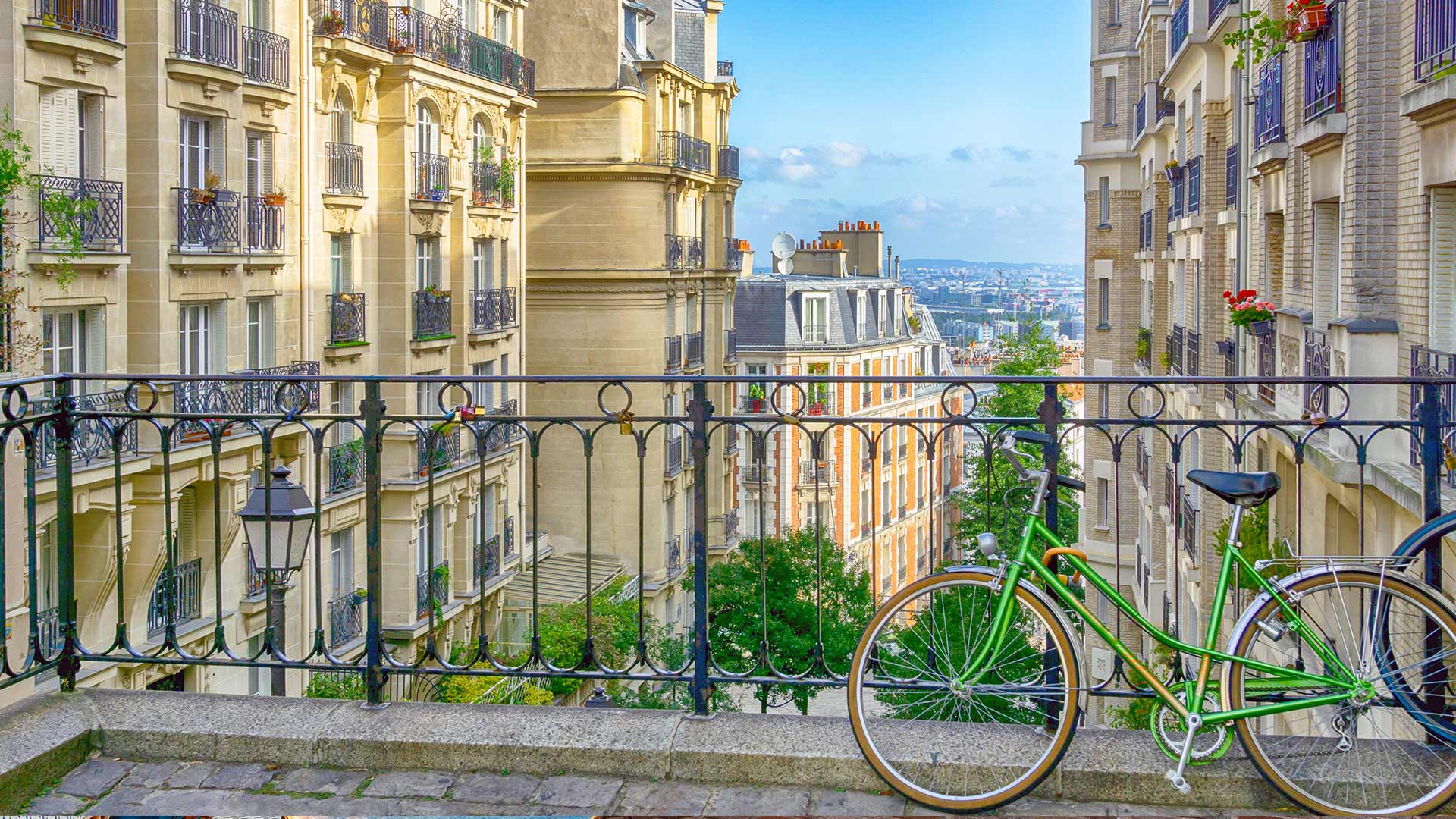 View of chic Paris buildings from Montmartre terrace with green bike leaning on it