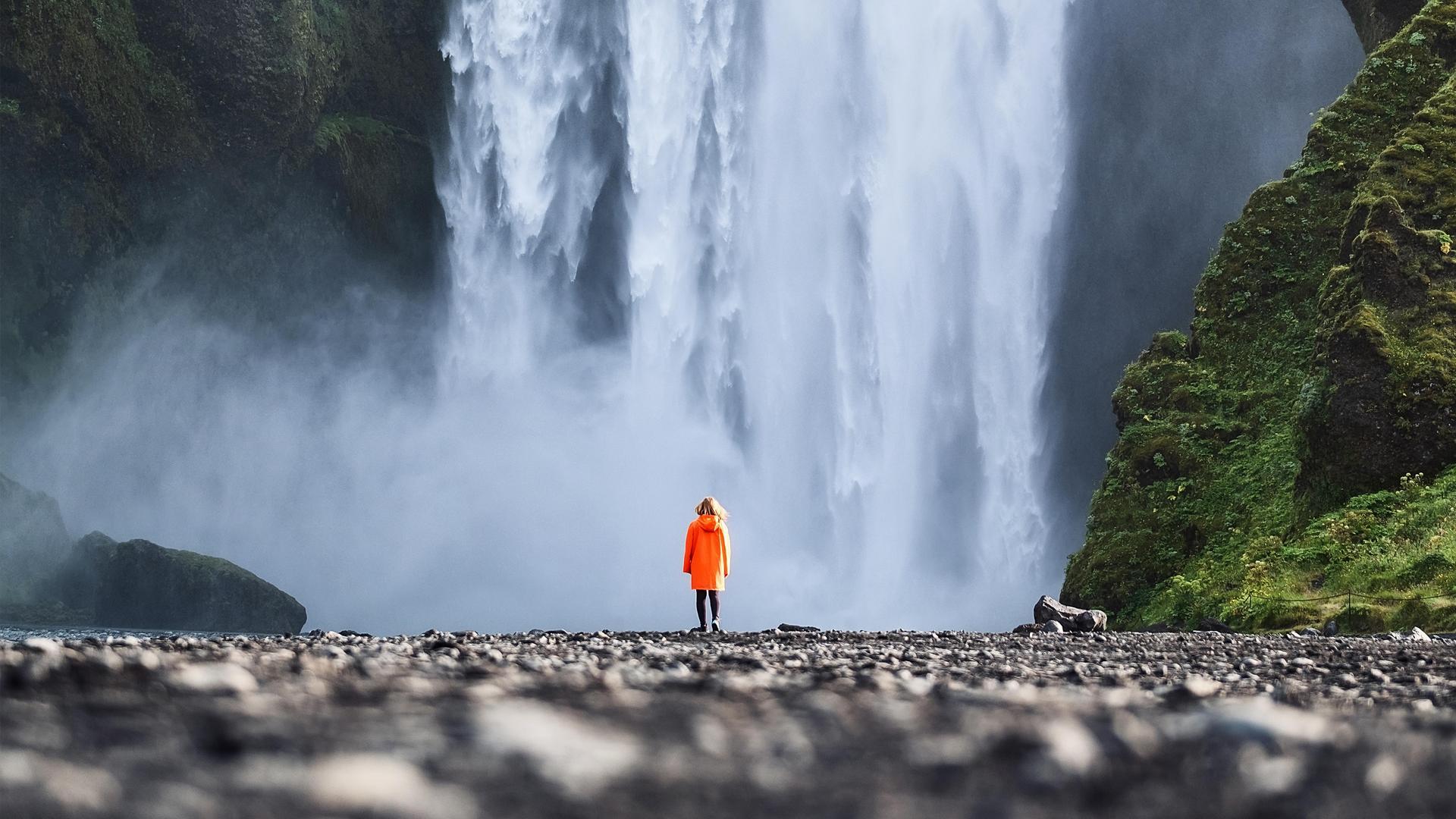 Person standing in front of Skogafoss waterfall