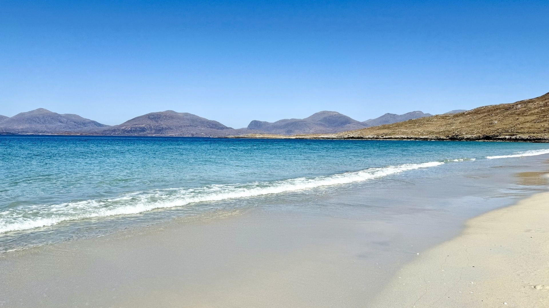 A tranquil beach with blue water lapping the pristine white sand.