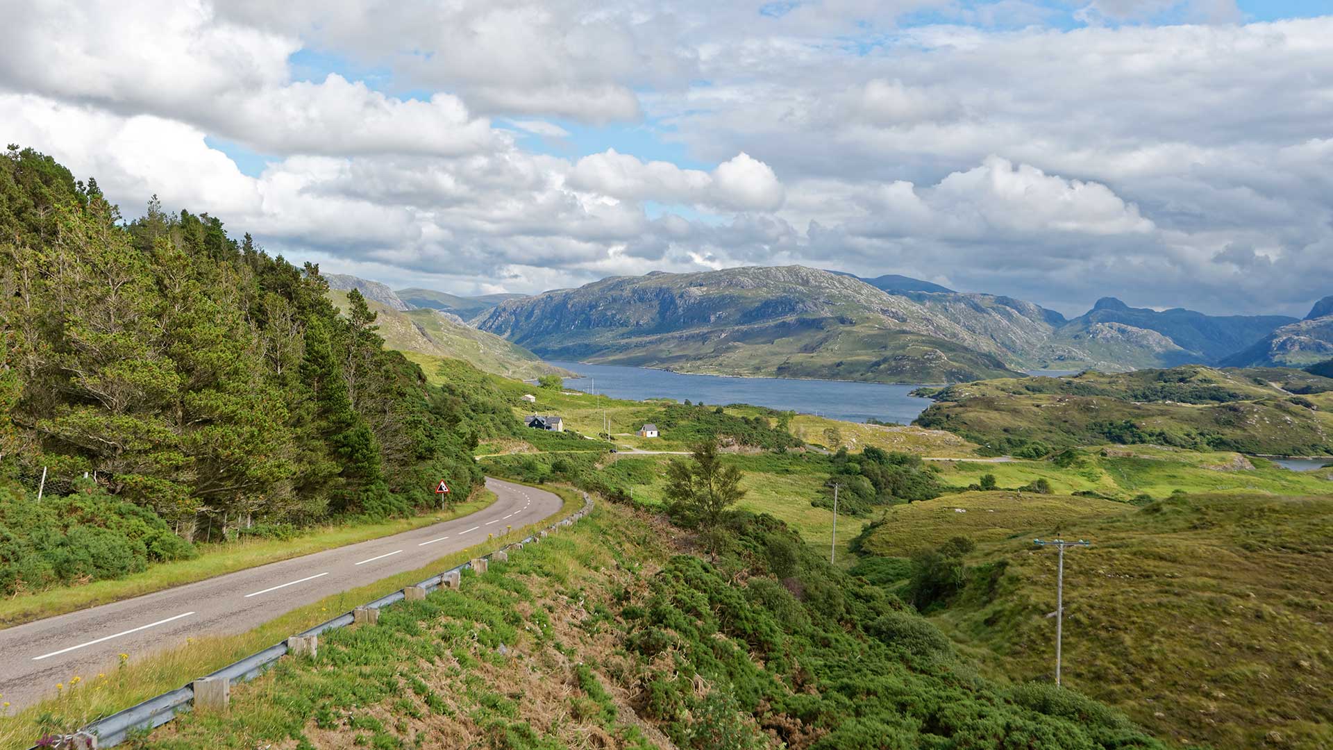 A winding road in Scotland's green landscapes, with Loch Glendhu behind.