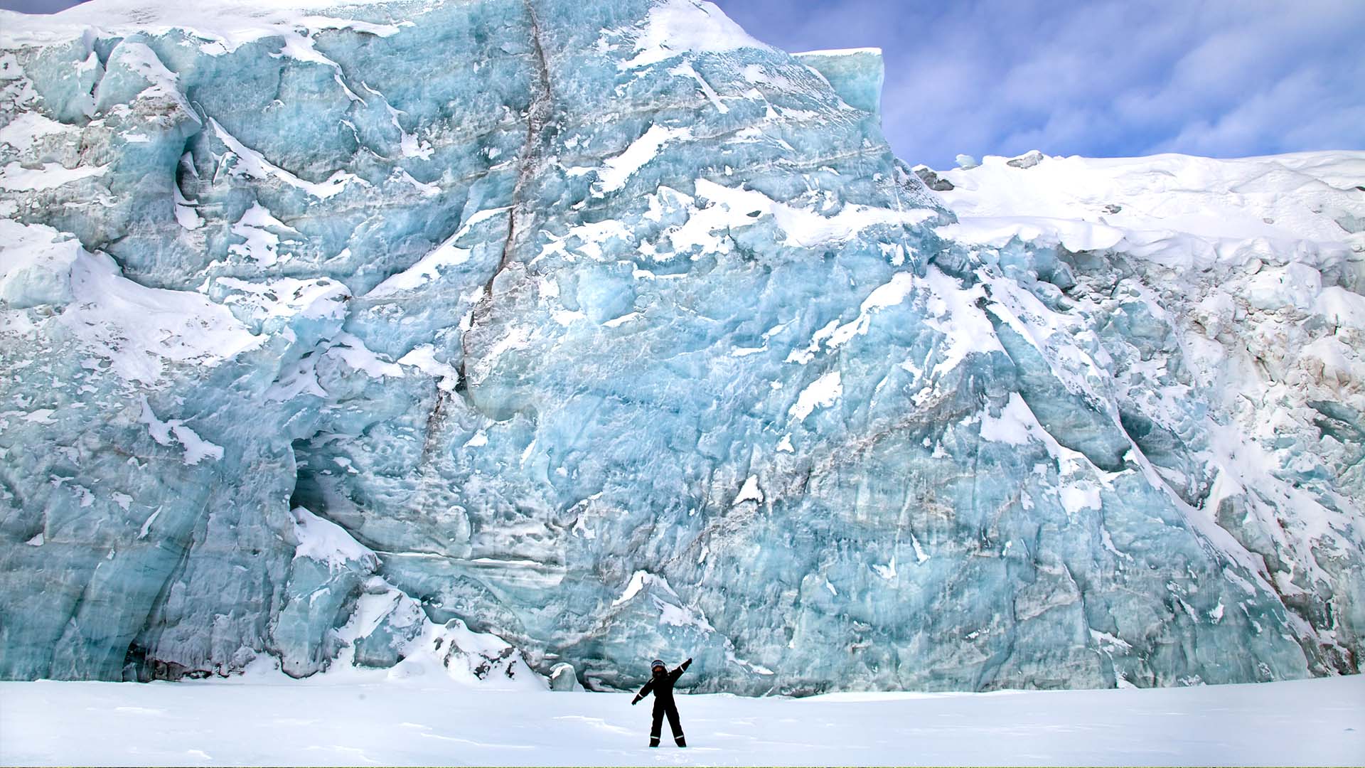 person standing in front of tall glacier