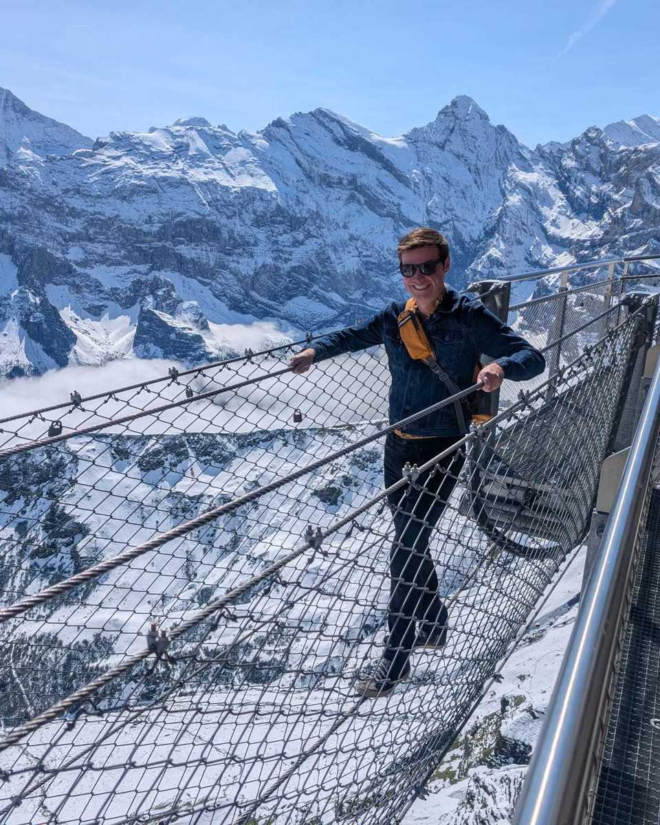 Customer Ethan on his Switzerland trip crossing a bridge across a snowy landscape