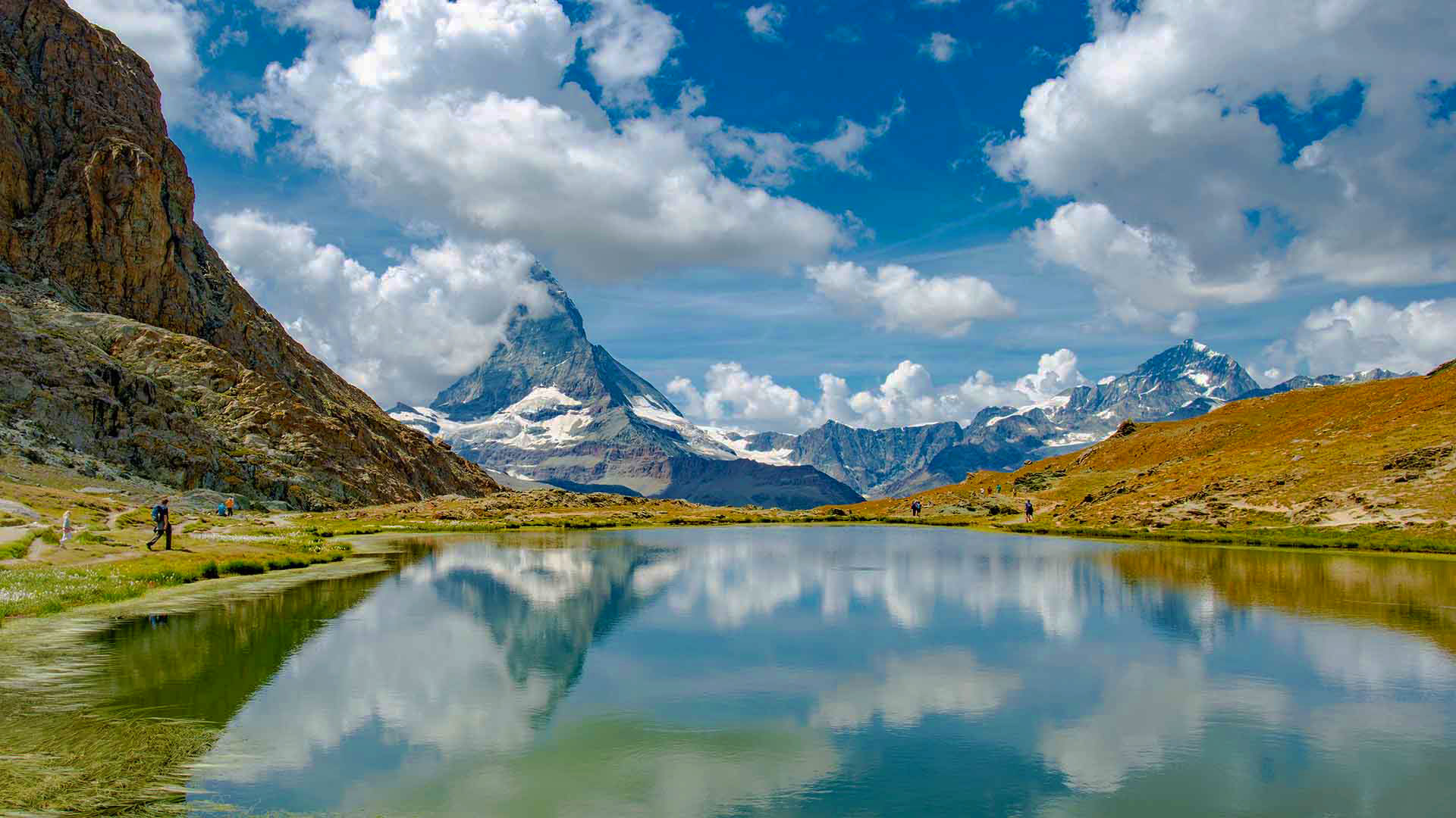 Matterhorn mountain with a lake and hikers in the foreground, Switzerland