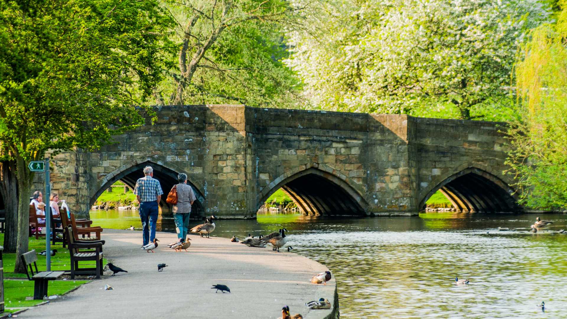 People strolling next to the calm river in Bakewell