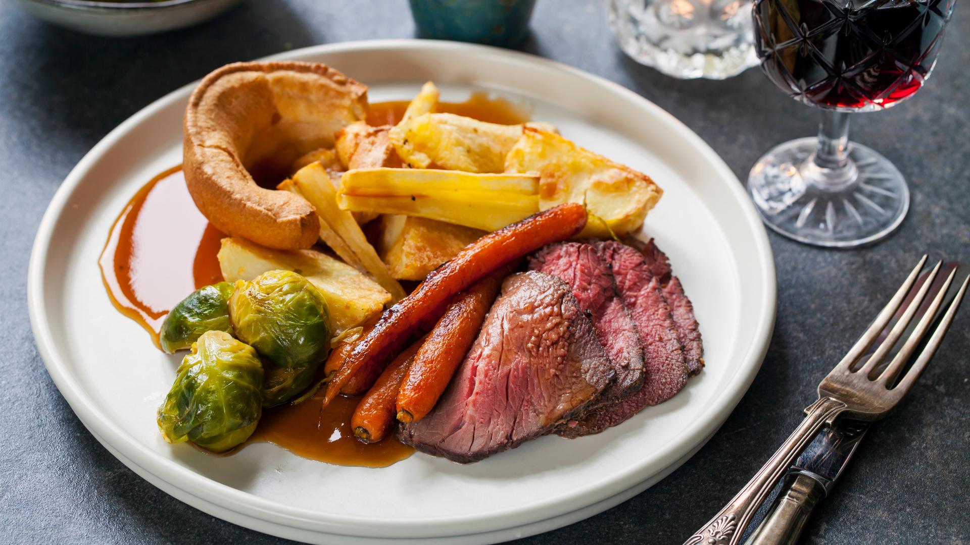 A tranditional roast dinner with soft beef, carrots, brussel sprouts and yorkshire pudding